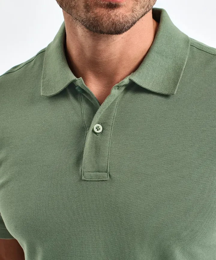 Gros plan sur la patte de boutonnage d'un polo vert sauge en maille piquée